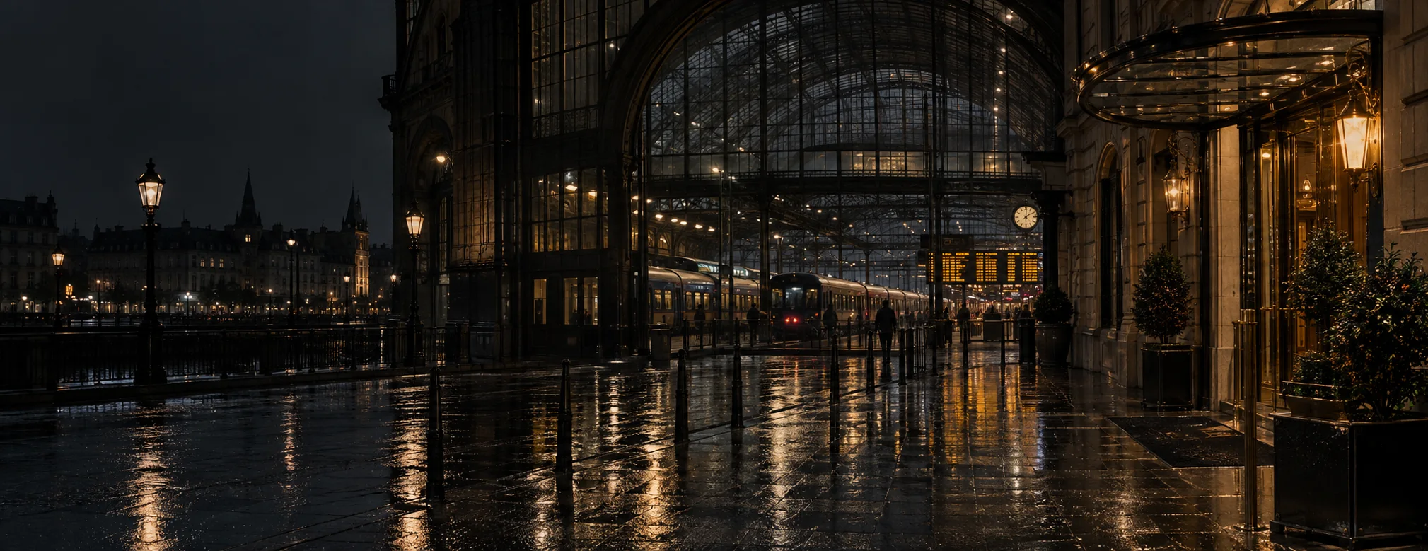 Natgeregende stenen voor een Europees treinstation, met een warm verlichte hotelingang dichtbij